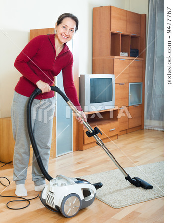 Happy mature woman cleaning with vacuum cleaner Happy mature woman cleaning with vacuum cleaner 9427767