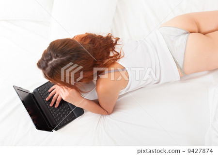woman with laptop on white sheet in bed at home woman with laptop on white sheet in bed at home 9427874
