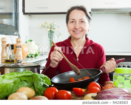 Positive mature woman cooking with skillet Positive mature woman cooking with skillet 9428083