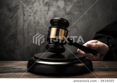 Judge's hand holding wooden hammer 9434095