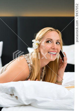 Young woman in Hotel reading book in bed 9437052