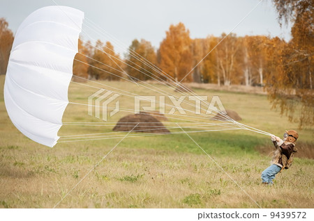 Little girl running with a parachute on the field in sunny autumn day Little girl running with a parachute on the field in sunny autumn day 9439572