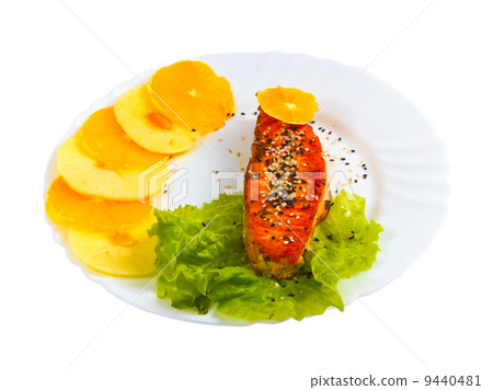 fried fish salmon with orange and apple leaf lettuce on plate is 9440481