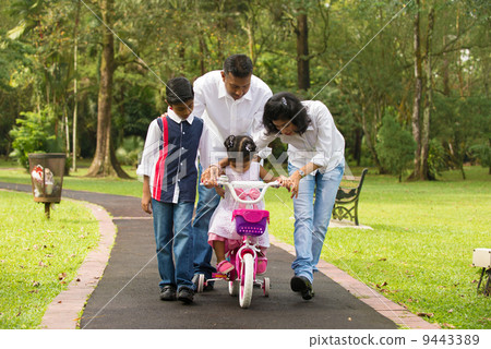 indian family guiding little daughter to cycle 9443389