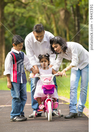 indian family guiding little daughter to cycle 9443391