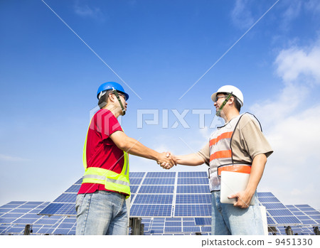 two engineers handshaking  before large solar power station 9451330