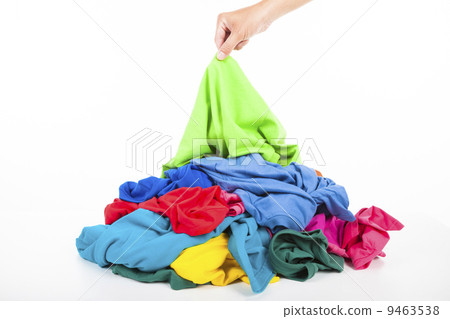hand pick up a shirt in pile of colorful clothes 9463538