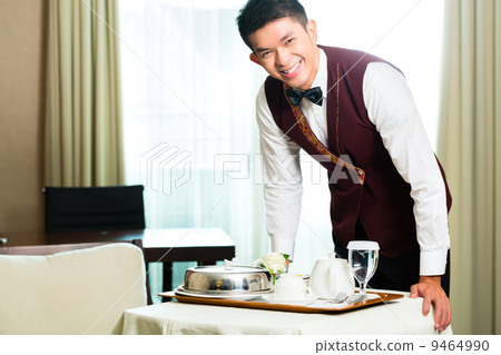 Asian Chinese room service waiter serving food in hotel 9464990