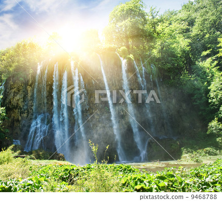 Sunrise over waterfall in wild forest 9468788