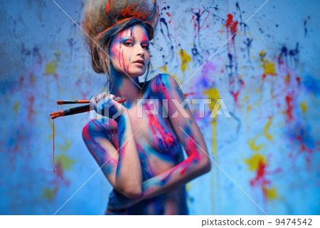 Young woman muse with creative body art and hairdo holding paint brushes 9474542