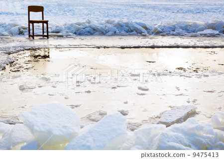 icebound chair near ice hole in frozen lake 9475413