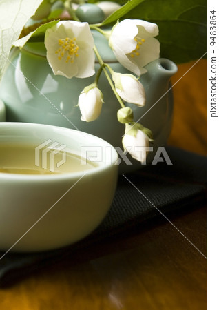 Green tea with jasmine in cup and teapot on wooden table Green tea with jasmine in cup and teapot on wooden table 9483864