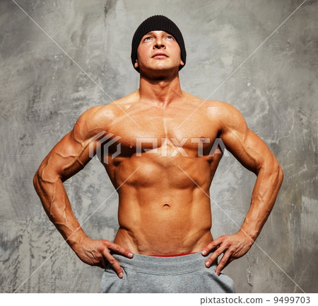 Handsome man with muscular torso in beanie hat posing 9499703
