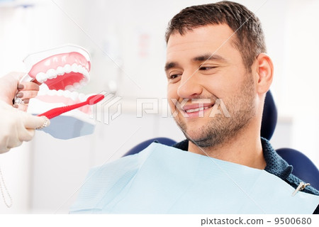 Dentist showing to man patient on mockup how to clean teeth Dentist showing to man patient on mockup how to clean teeth 9500680