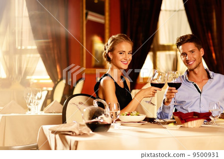 Beautiful young couple with glasses of red wine in luxury restaurant 9500931