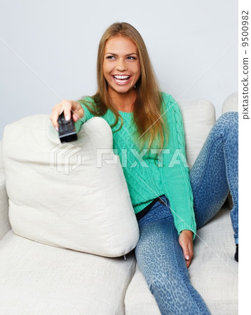 Young beautiful woman on a sofa with remote control 9500982