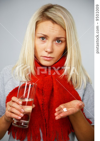 Sick young blond woman with pills and glass of water 9501009