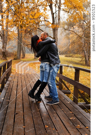 Happy middle-aged couple kissing outdoors on beautiful autumn day 9501523