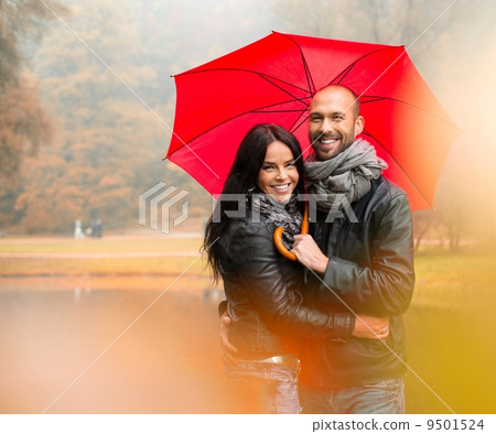 Happy middle-aged couple with umbrella outdoors on beautiful rainy autumn day 9501524