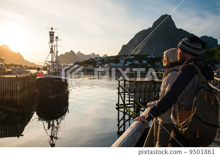 Young travellers couple looking at sunset in Reine village, Norway Young travellers couple looking at sunset in Reine village, Norway 9501861