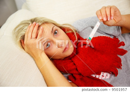 Sick young woman with thermometer lying on sofa at home Sick young woman with thermometer lying on sofa at home 9501957