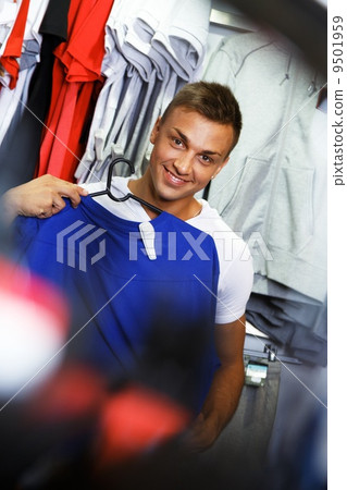 Handsome young man choosing sports wear in a sport outlet Handsome young man choosing sports wear in a sport outlet 9501959