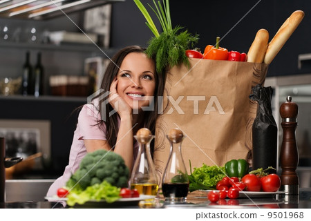 Young woman with grocery bag full of fresh vegetables on a modern kitchen Young woman with grocery bag full of fresh vegetables on a modern kitchen 9501968