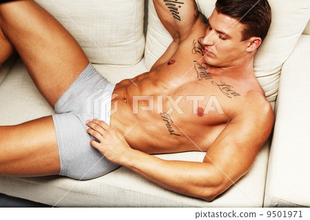 Man with beautiful muscular tattooed torso in underwear lying on sofa Man with beautiful muscular tattooed torso in underwear lying on sofa 9501971