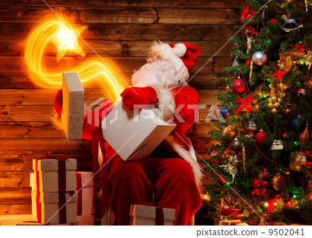 Santa Claus in wooden home interior holding gift box with magic star flying out of it 9502041