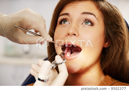Dentist making anaesthetic injection to woman patient 9502377