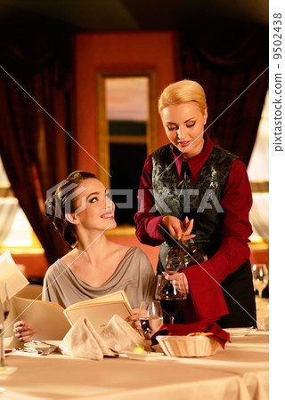 Beautiful young girl in restaurant and waitress pouring wine Beautiful young girl in restaurant and waitress pouring wine 9502438