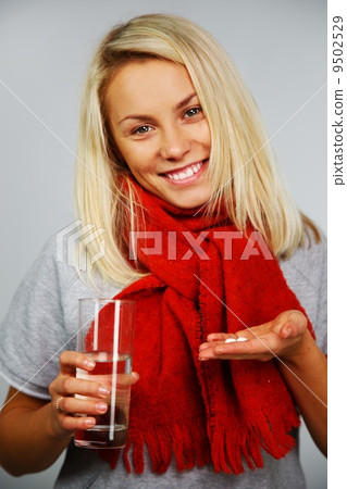 Sick young blond woman with pills and glass of water Sick young blond woman with pills and glass of water 9502529