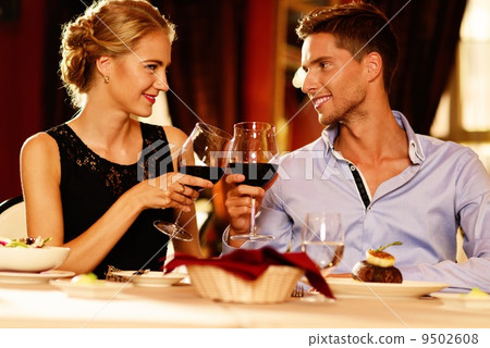 Beautiful young couple with glasses of red wine in luxury restaurant 9502608