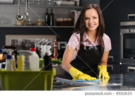 Beautiful cheerful brunette woman in gloves cleaning modern kitchen 9502633