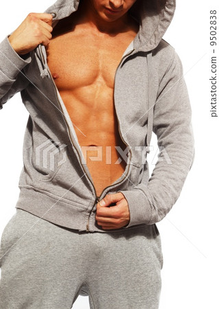 Handsome man in grey hoodie showing his abdominal muscles 9502838