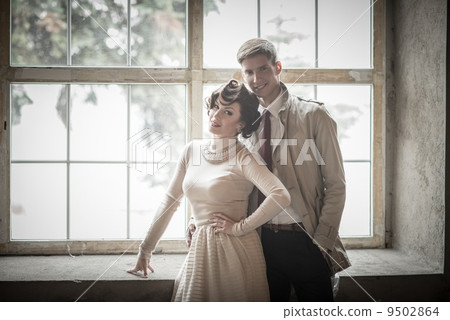 Beautiful vintage style couple standing near window 9502864