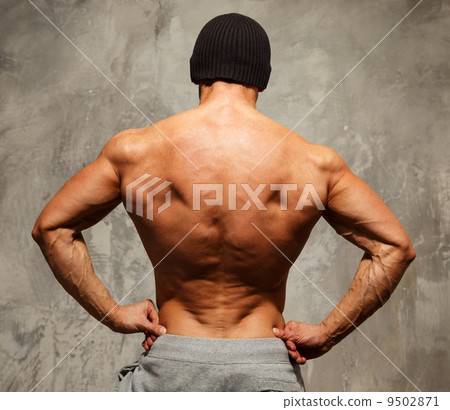 Handsome man with muscular torso in beanie hat posing 9502871