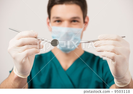 Young male dentist holding dental tools 9503118