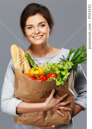 Smiling young brunette woman with grocery bag full of fresh vegetables Smiling young brunette woman with grocery bag full of fresh vegetables 9503581