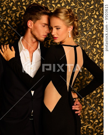 Beautiful well-dressed couple standing against abstract wall 9503615