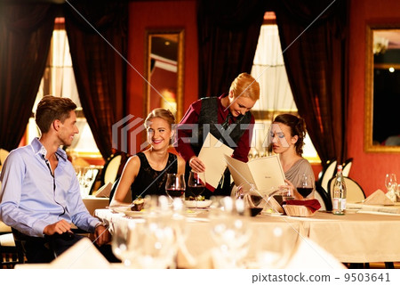 Group of young friends with menus choosing in a luxury restaurant 9503641
