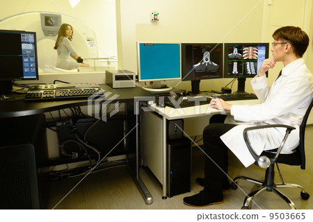 Young doctor sitting behind monitors in a computed tomography laboratory Young doctor sitting behind monitors in a computed tomography laboratory 9503665