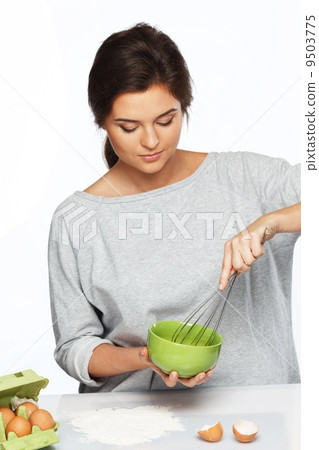 Young woman whisking eggs for a dough Young woman whisking eggs for a dough 9503775