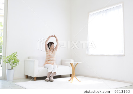 Mature lady sitting on the sofa and stretching out 9513163