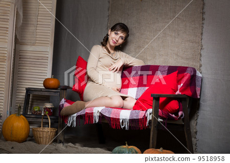 Young pregnant woman sitting on sofa Young pregnant woman sitting on sofa 9518958