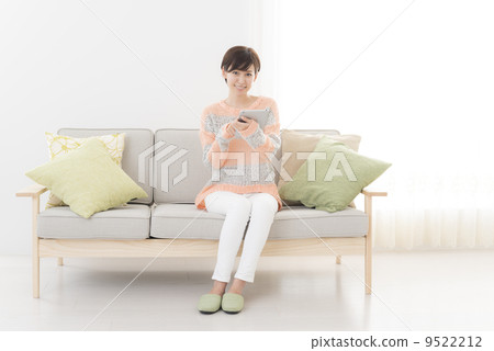 A woman sitting on a net search sofa and searching with a tablet 9522212