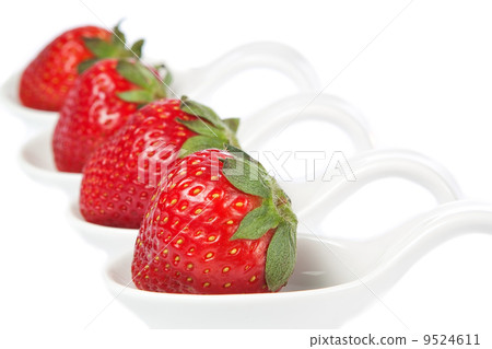 Group of strawberries on a porcelain spoon. On a white backgroun 9524611