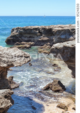 Sailboat on the horizon in the sea near the rocks. 9524830