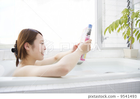 A woman reading a magazine while taking a bath A woman reading a magazine while taking a bath 9541493