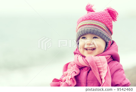 Happy baby girl in a pink hat and scarf 9542460
